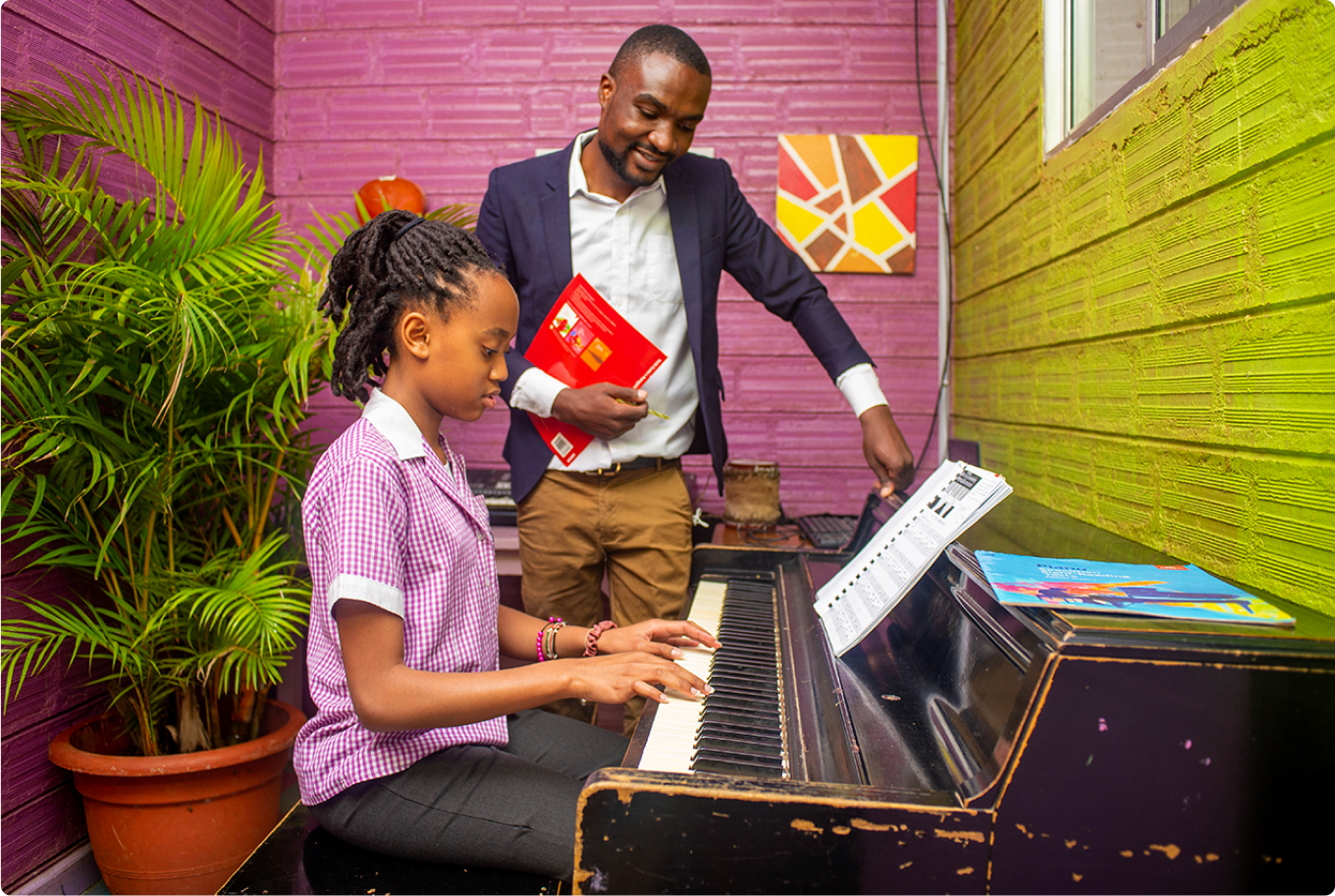 Riara primary school pupil playing keyboard with teacher supervision