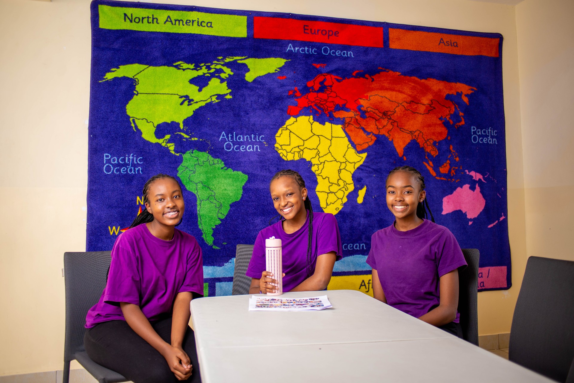 3 Riara springs girls high school students in a room with the map of the world hang on the wall