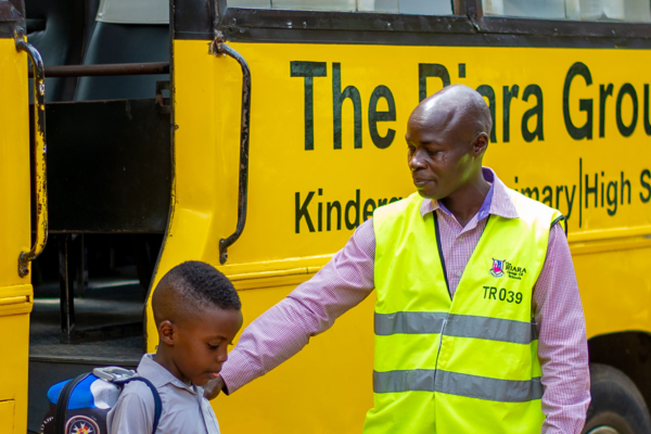 Riara group of schools bus attendant helping a primary school pupil alight