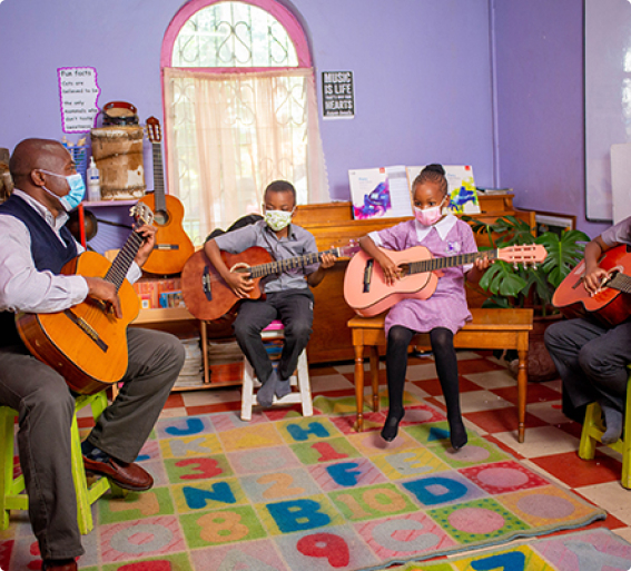 Riara primary school pupils seated in music class playing guitars with male teacher